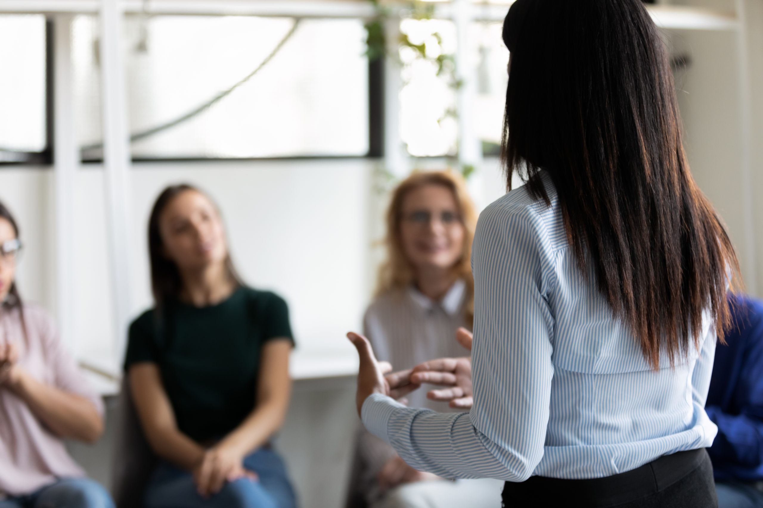 mujer de espalda dando discurso a mujeres